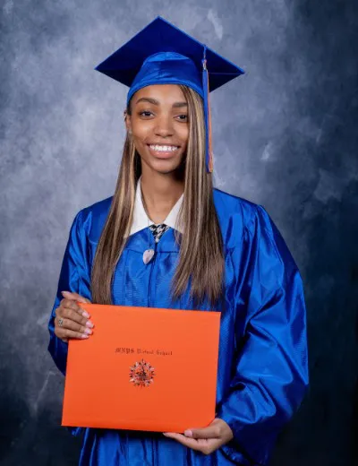 A picture of Jeyda, the graduate, smiling and holding her diploma.